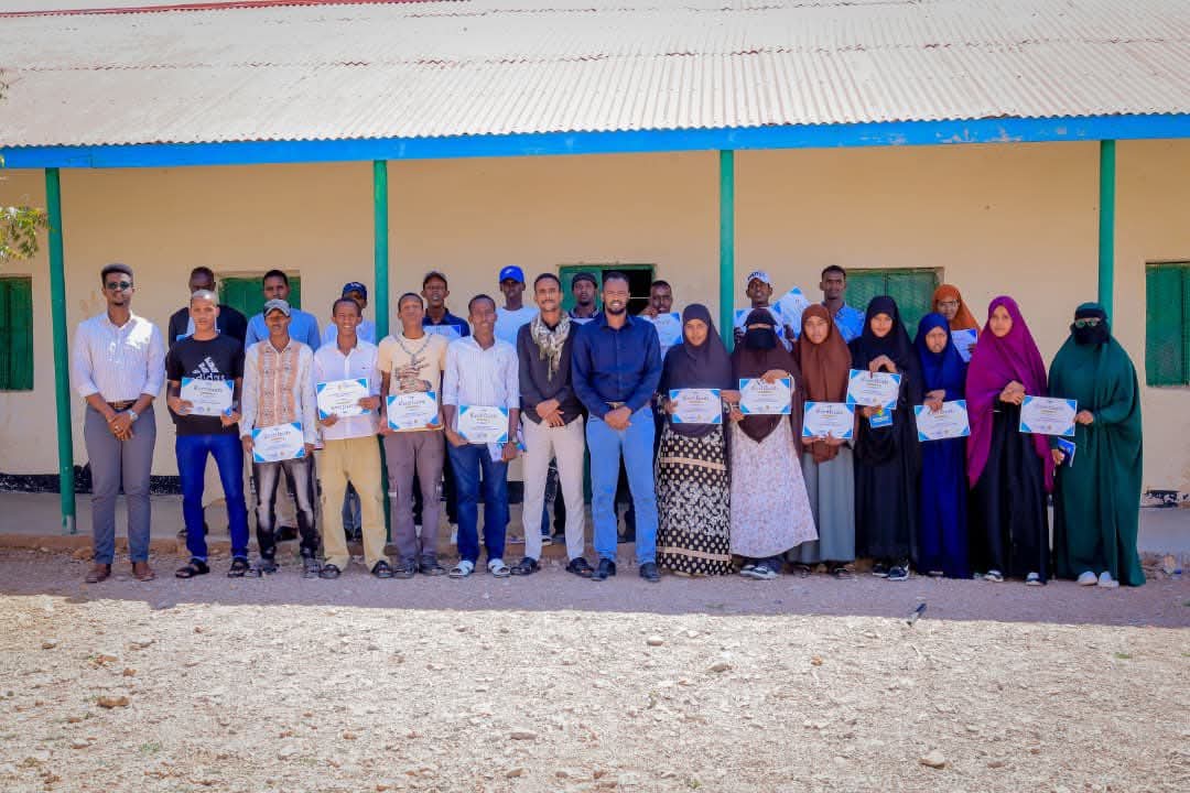 A group standing outside a building and holding certificates